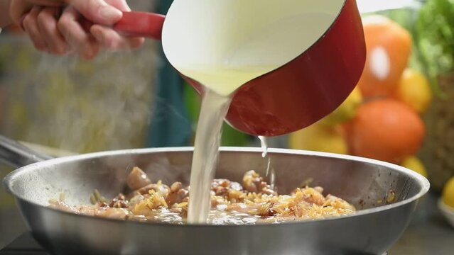 The chef adds chicken stock to the chicken with orzo pasta.
