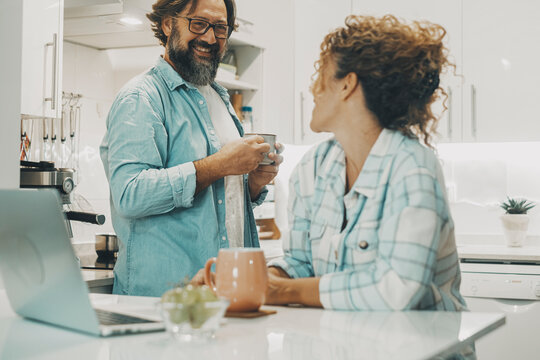 Happy couple adult man adn woman in indoor leisure activity together happy and smiling. Family people real life concept in the kitchen. Mature in relationship. Morning breakfast in apartment inside