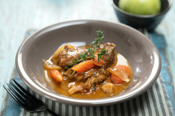 Braised pork shoulder, served on the plate, close-up.

