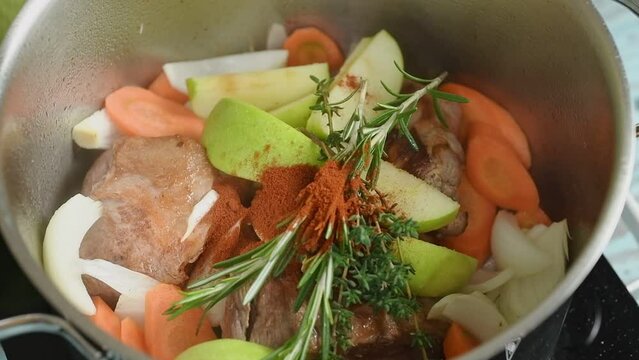 Adding smoked paprika to the braised pork shoulder in a pot.
