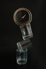 Three transparent glasses stacked with a compass atop in balance concept