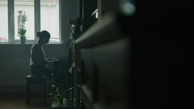 female playing piano in her home. Cinematic setting. classical music in slow motion. 