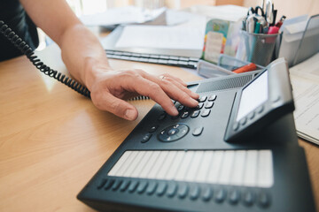 Left-handed man's hand dialing the office telephone