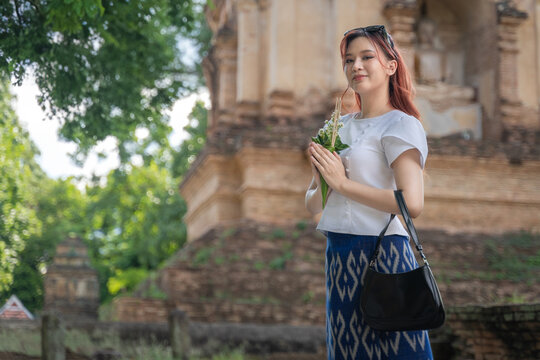 Pretty Asian tourist woman wearing beautiful Modern Thai traditional dress costumes in the ancient Wat Chet Yot Temple (Wat Jed Yod) an Old seven-pagoda Buddhist temple Chiang Mai, Thailand