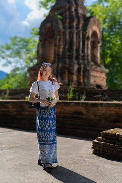 Pretty Asian tourist woman wearing beautiful Modern Thai traditional dress costumes in the ancient Wat Chet Yot Temple (Wat Jed Yod) an Old seven-pagoda Buddhist temple Chiang Mai, Thailand