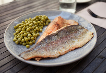 Appetizing baked trout fillets with green peas