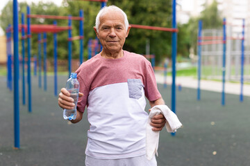 Elderly man is resting and drinking water from a bottle