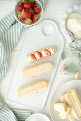 The process of making a dessert of Savoyard cookies, strawberries and buttercream. The photo is part of a group of photos where the creation of the dessert is shown step by step