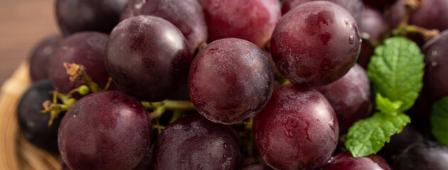 Delicious bunch of grapes fruit on a plate over wooden table background.