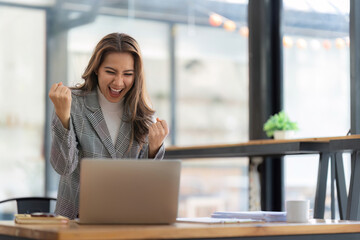 Excited business woman surprise looking on laptop having a good news