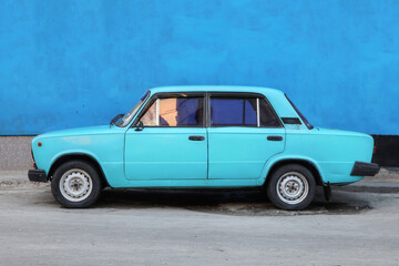 A Monochrome photo of a blue car in front of a blue wall in Havana Cuba