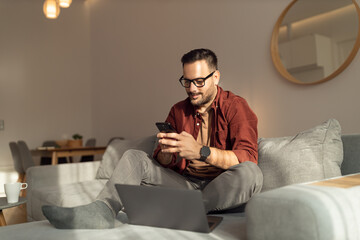 Smiling man chatting with someone over the mobile phone while sitting at home.