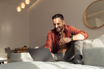 Fototapeta premium Man relaxing at home, watching something online, sitting on the couch.