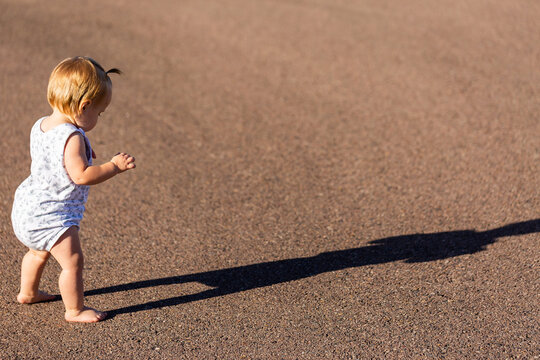 Toddler with long shadow walking across road