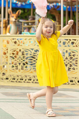 Little girl with cotton candy in an amusement park. The concept of summer holidays and school holidays