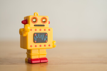 Fototapeta premium Yellow cute retro AI robot toy on wooden background copy space. Artificial intelligence (AI), digital future technology, smart brain computer concept.