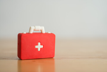 Red first aid bag suitcase toy on wooden background with copy space. First aid kit, healthcare , medical and hospital concept. - obrazy, fototapety, plakaty