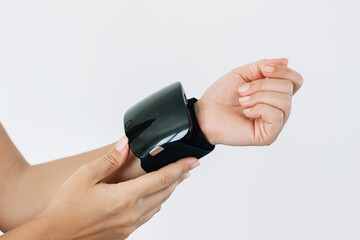 Automatic electronic blood pressure monitor on a woman's wrist isolated on white background. A...