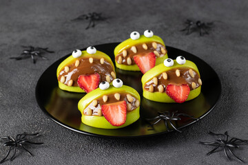 Spooky green apple monsters for Halloween party on dark gray background decorated with spiders