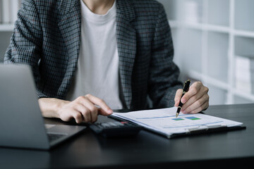 Businessman working on calculator to calculate financial data report, accountancy document and laptop computer at office, business concept.