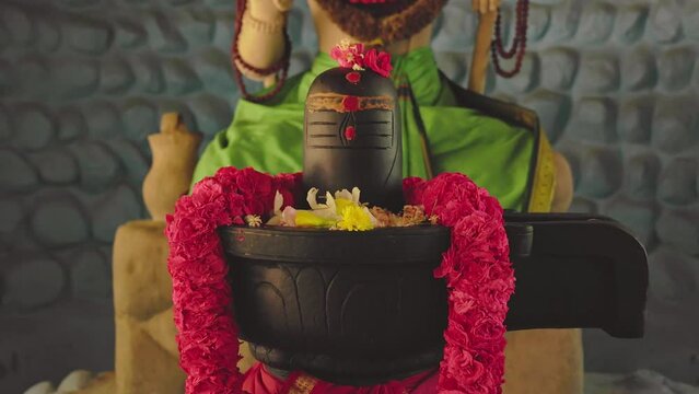 Closeup of lord shiva or shivling stone idol adorned with garlands at temple