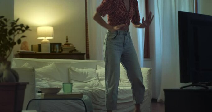 Young Stylish Brazilian Woman in Stylish Clothes Dancing to the Beat of a Song in her Apartment. Beautiful Carefree Female with Curly Hair Enjoying her Time By Moving Along Happy Music