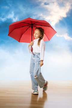 Cute little girl with umbrella on clouds sky background.