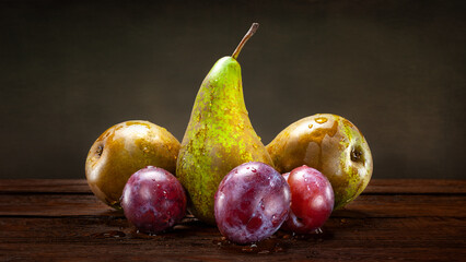 Wet pear and plums with water drops. Pear and plums on abstract grunge background