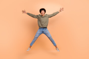 Fototapeta na wymiar Full size photo of overjoyed cheerful young man jumping make star figure isolated on beige color background