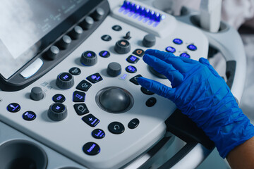 Close-up of the hands of a female ultrasound doctor while working with a modern ultrasound machine.