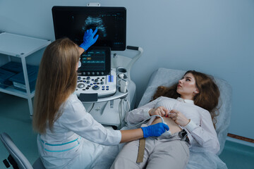 The doctor shows the patient on the screen of a modern ultrasound machine during an examination at...