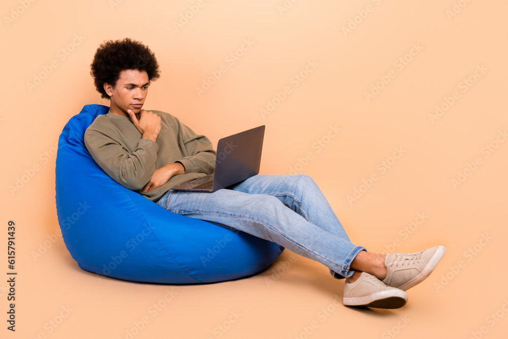 Sticker Full body length photo of smart team lead it specialist young man developer work sit bean bag touch chin laptop isolated on beige color background