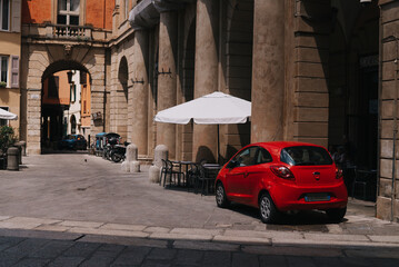 Red car in front of a building in Bologna, Italy - obrazy, fototapety, plakaty