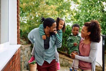 Cheerful black parents have fun with their kids outdoors.
