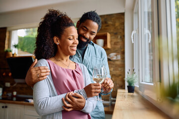 Fototapeta premium Happy black couple toasting while drinking wine at home.
