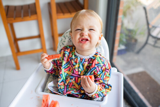 Happy baby pulling silly face eating watermelon for a snack