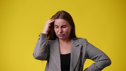 4k video of one woman who scratching her head and thinking about something over yellow background.