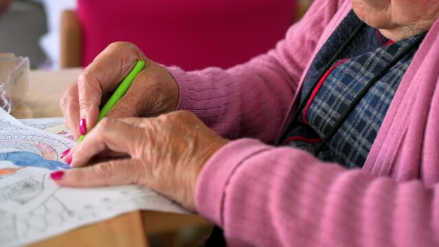 Elderly woman painting color on her drawing. Hobby at nursing home. High quality 4k footage