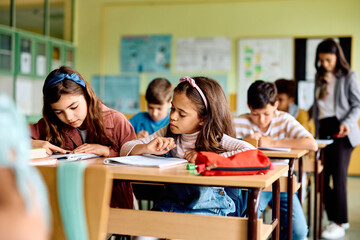Hispanic schoolgirl learning while attending class in classroom.