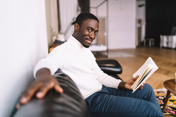 Delighted man on sofa with book