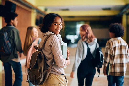 Happy black teenage girl in high school hallway looking at camera. - Powered by Adobe