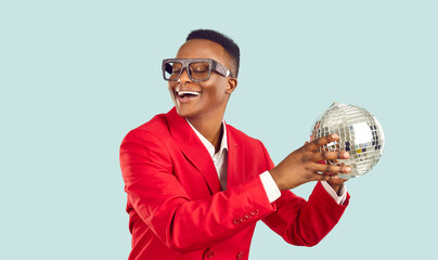 Stylish and cool African American man smiling happily with disco ball in his hands. Man in red suit...