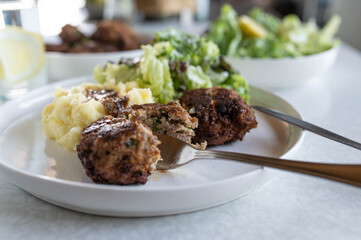 German meatballs with mashed potatoes and salad on a dinner table
