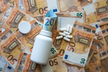 White jar with pills close-up on the background of the euro currency.