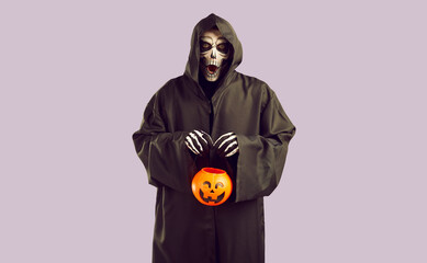 Man in grim reaper costume with creepy facial expression collects candy during Halloween...