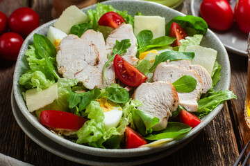 Salad of chicken fillet, eggs, tomatoes and cheese in a plate. Caesar salad