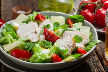 Salad of chicken fillet, eggs, tomatoes and cheese in a plate. Caesar salad