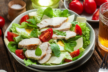 Salad of chicken fillet, eggs, tomatoes and cheese in a plate. Caesar salad