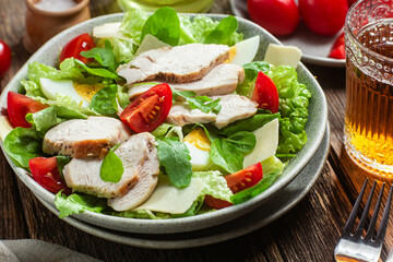 Salad of chicken fillet, eggs, tomatoes and cheese in a plate. Caesar salad