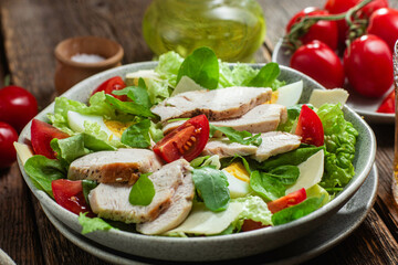 Salad of chicken fillet, eggs, tomatoes and cheese in a plate. Caesar salad